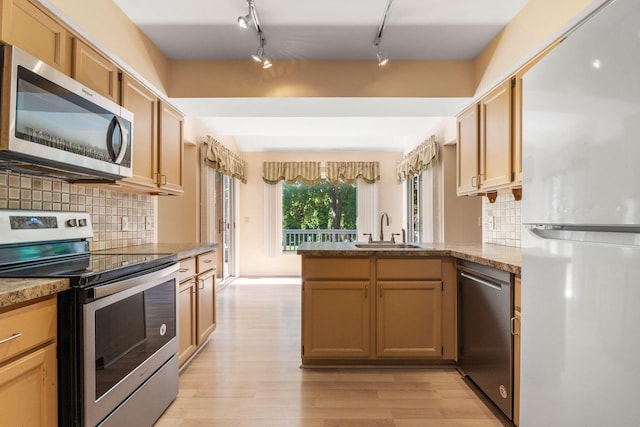 6360 Robison Ln, Saline, MI 48176 - kitchen featuring a peninsula, light wood-style floors, a sink, backsplash, and stainless steel appliances