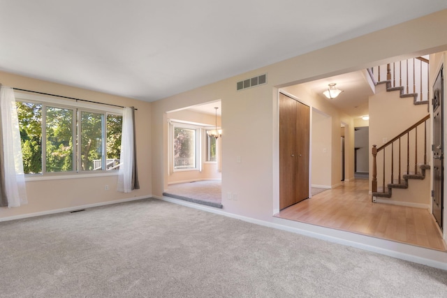 6360 Robison Ln, Saline, MI 48176 - carpeted empty room with a chandelier, visible vents, and stairway