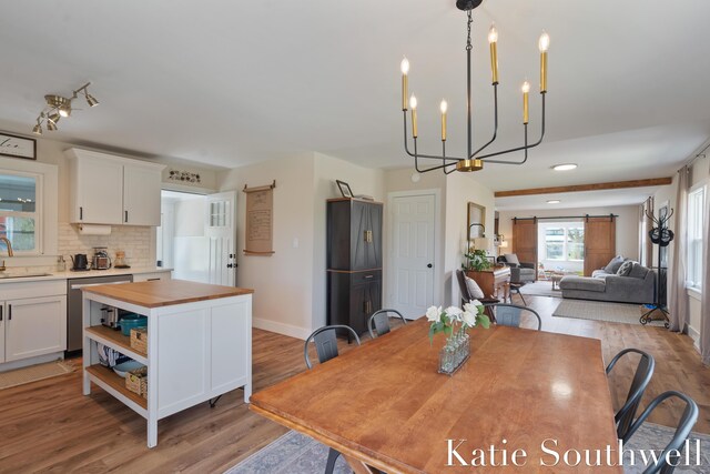 dining space featuring light wood-style floors, baseboards, a barn door, and a chandelier