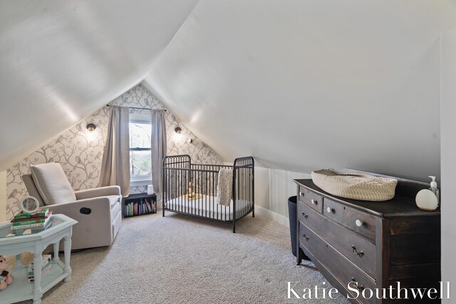 carpeted bedroom with a nursery area and lofted ceiling