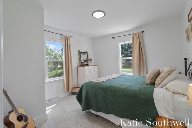 bedroom featuring baseboards, visible vents, multiple windows, and carpet