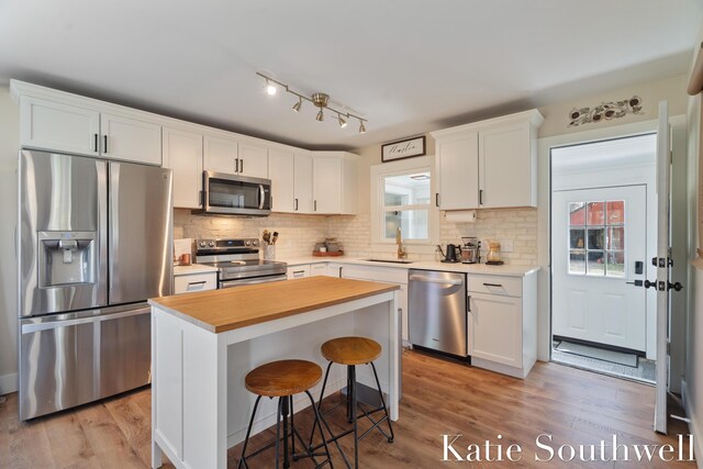 kitchen with backsplash, white cabinetry, appliances with stainless steel finishes, and a sink