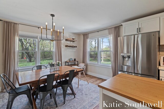 dining space featuring baseboards, light wood-style flooring, and a chandelier