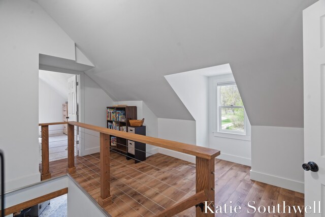 additional living space featuring baseboards, wood finished floors, and vaulted ceiling