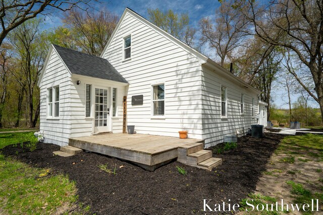 rear view of property with roof with shingles, central AC, and a deck