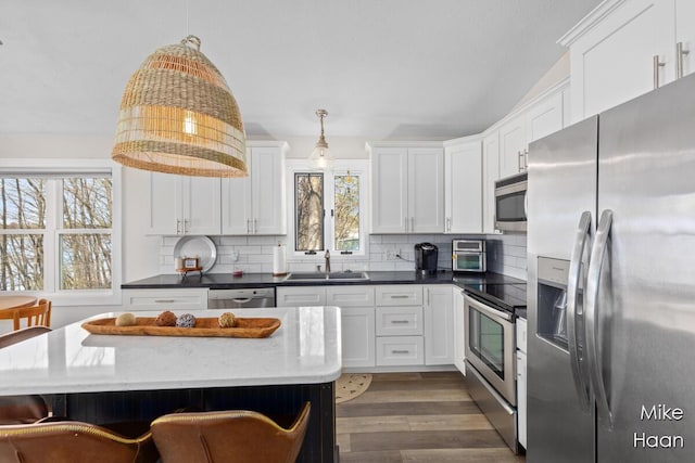 kitchen with a sink, appliances with stainless steel finishes, tasteful backsplash, and white cabinetry