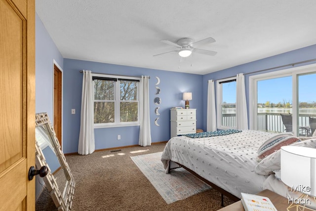 carpeted bedroom with access to outside, baseboards, a ceiling fan, and a water view