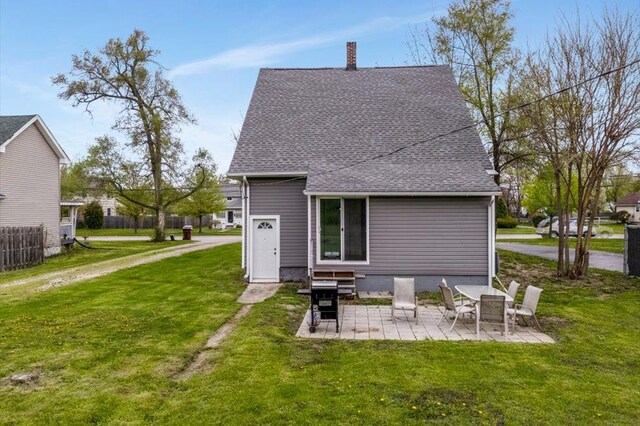 rear view of property featuring a patio, a shingled roof, a yard, and a chimney