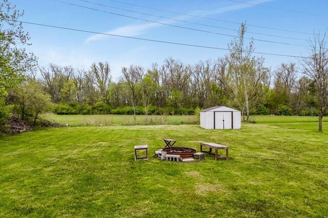 view of yard featuring a storage shed, a fire pit, and an outdoor structure