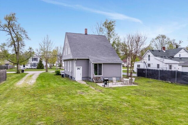 rear view of property featuring entry steps, fence, a patio, and a yard