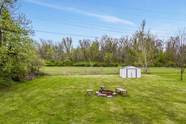 view of yard featuring an outdoor structure, a fire pit, and a shed