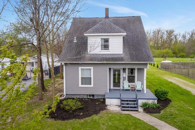 exterior space featuring fence, roof with shingles, a front lawn, a porch, and a chimney