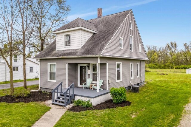 rear view of house with covered porch, a chimney, a lawn, cooling unit, and a shingled roof