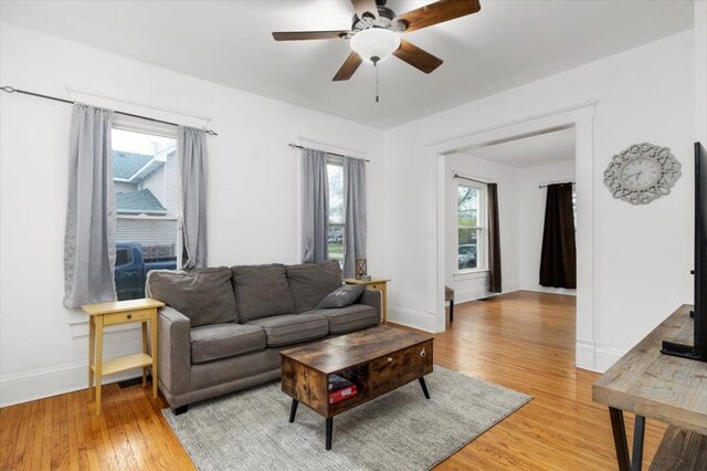 living area featuring light wood-type flooring, baseboards, and ceiling fan