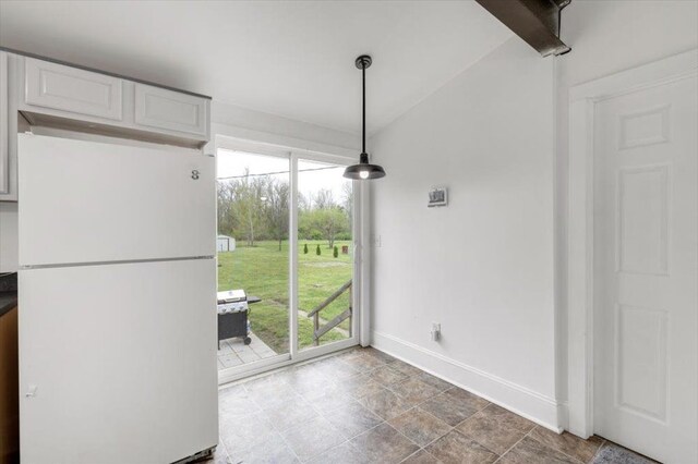 unfurnished dining area featuring baseboards, stone finish flooring, and a wealth of natural light