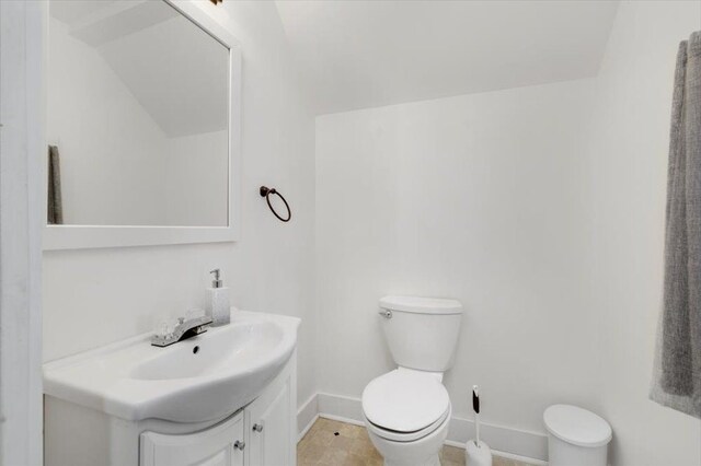 half bathroom featuring toilet, baseboards, and vanity