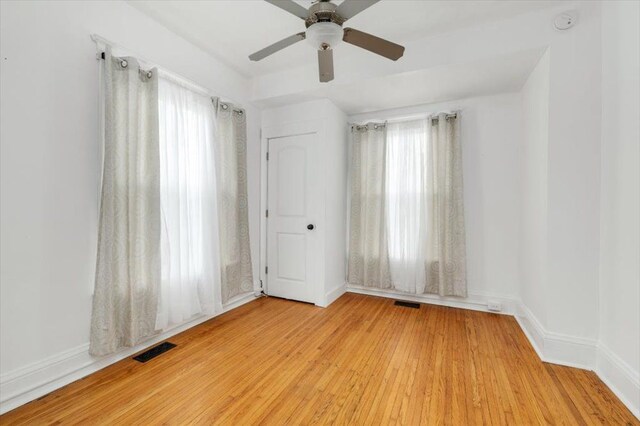 unfurnished room featuring visible vents, a ceiling fan, baseboards, and wood finished floors