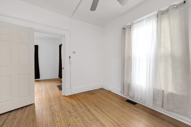 spare room featuring a ceiling fan, light wood finished floors, and visible vents