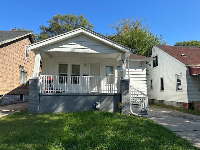 bungalow-style house with covered porch, a front yard, board and batten siding, and stairway
