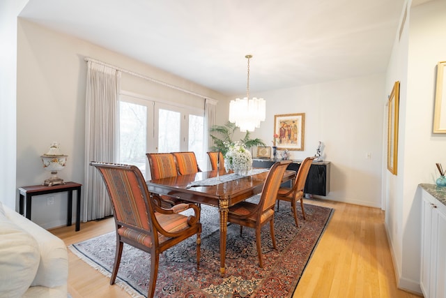 dining space featuring an inviting chandelier, light wood-style flooring, and baseboards