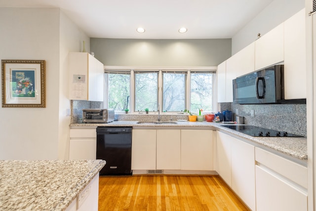 kitchen featuring a sink, decorative backsplash, black appliances, and a healthy amount of sunlight