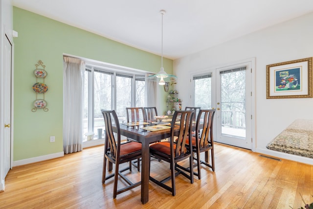 dining room with baseboards, visible vents, and light wood-type flooring