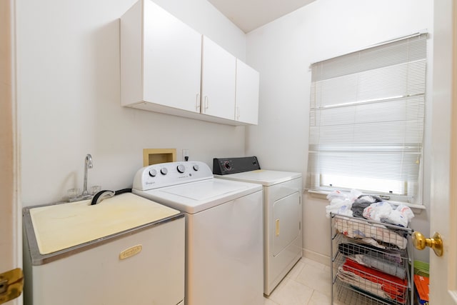 laundry room featuring cabinet space, light tile patterned floors, washing machine and dryer, and a sink