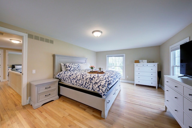 bedroom featuring baseboards, light wood finished floors, and visible vents