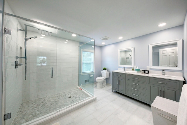 bathroom featuring a sink, toilet, marble finish floor, visible vents, and a shower stall