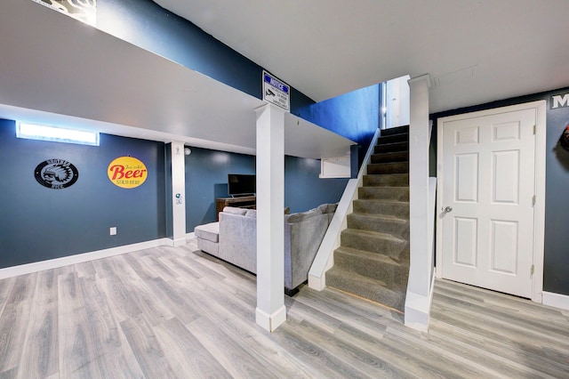 basement with stairs, baseboards, and wood finished floors