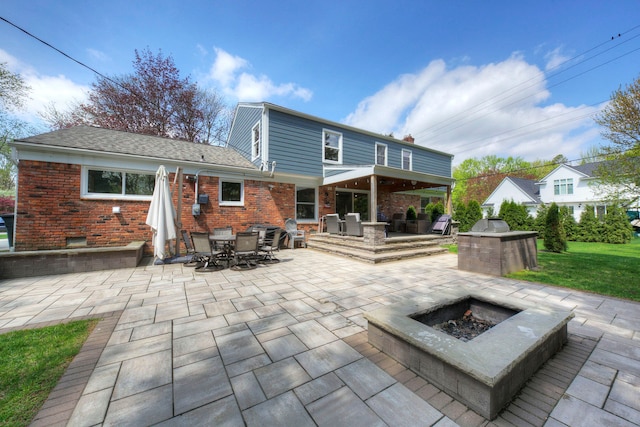 back of property featuring an outdoor fire pit, a patio area, brick siding, and outdoor dining space