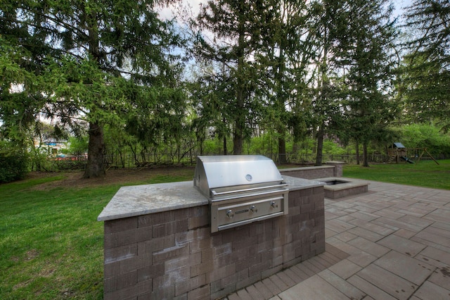 view of patio with area for grilling, a playground, fence, and a grill