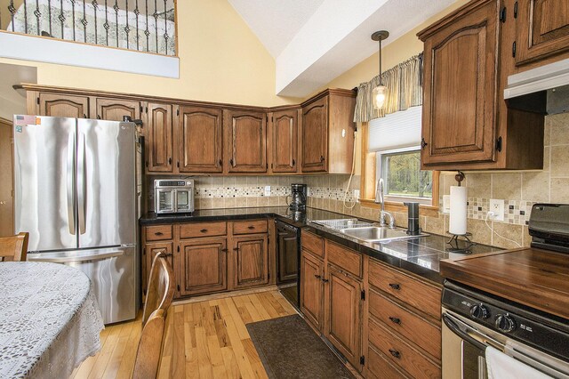 kitchen with freestanding refrigerator, dark countertops, oven, a sink, and dishwasher