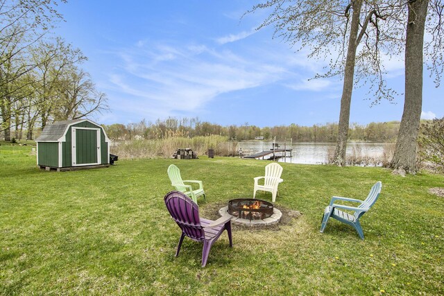 view of yard featuring a storage unit, an outbuilding, a water view, and an outdoor fire pit