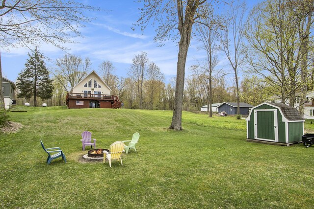 view of yard featuring a storage shed, an outdoor structure, an outdoor fire pit, and a wooden deck