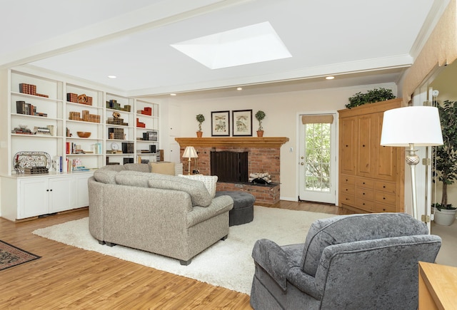 living room with a skylight, crown molding, a brick fireplace, and light wood finished floors