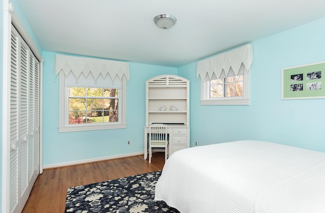 bedroom with baseboards, wood finished floors, and multiple windows