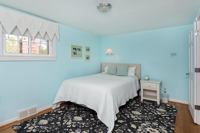 bedroom with visible vents, baseboards, and wood finished floors