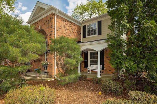 view of property exterior with brick siding and a porch