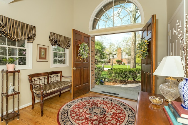 foyer featuring visible vents, baseboards, a towering ceiling, and wood finished floors