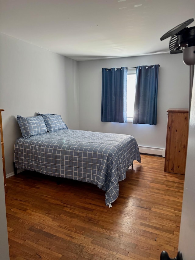 bedroom featuring wood finished floors and a baseboard radiator