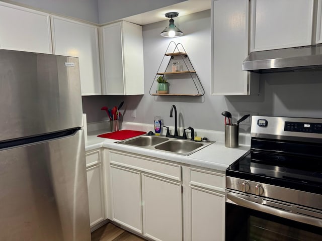 kitchen with under cabinet range hood, white cabinetry, appliances with stainless steel finishes, and a sink