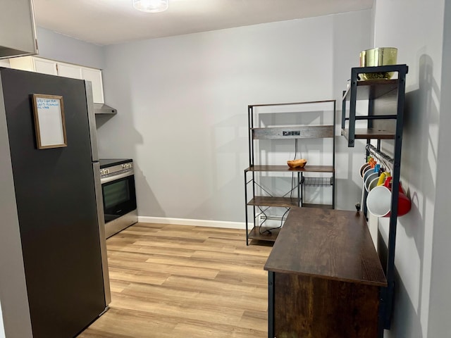 kitchen with light wood-type flooring, wall oven, baseboards, freestanding refrigerator, and white cabinetry