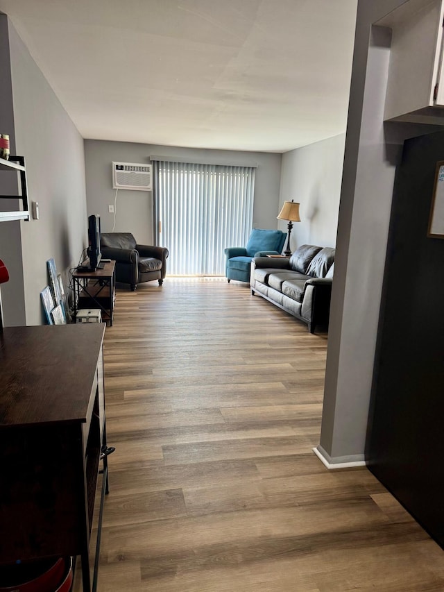 living room featuring a wall unit AC and wood finished floors