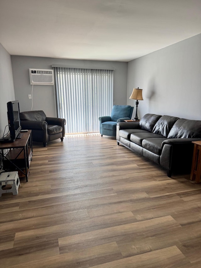 living room with a wall mounted air conditioner and wood finished floors