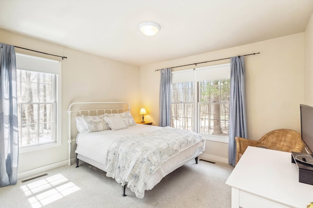bedroom with baseboards, light colored carpet, and visible vents