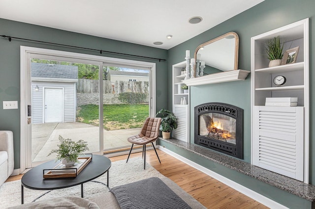living room featuring a glass covered fireplace and wood finished floors