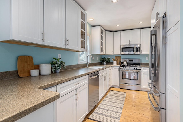 kitchen with a sink, glass insert cabinets, stainless steel appliances, recessed lighting, and white cabinetry