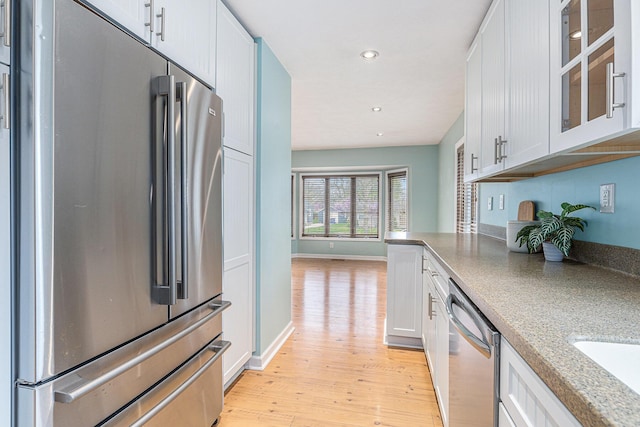 kitchen with glass insert cabinets, recessed lighting, white cabinets, light wood-style flooring, and appliances with stainless steel finishes