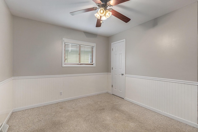 spare room featuring ceiling fan, wainscoting, and carpet